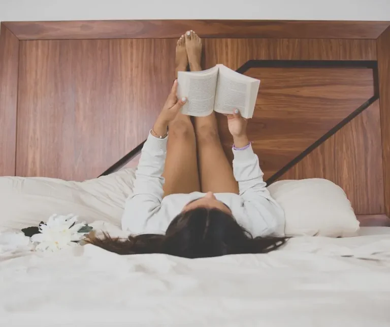 Libri che aprono prospettive diverse. Una donna legge un libro sdraiata con le gambe verso l'alto